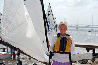 Kay at 11 years old, ready to launch her Opti off the beach of her local sailing club
